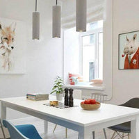 Suspension LED allongée en ciment gris.